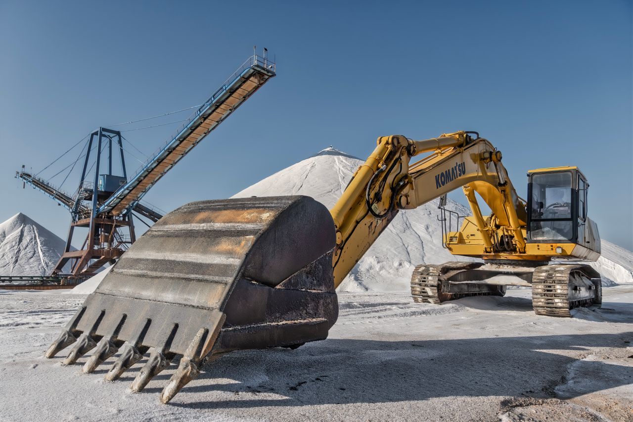 creative-01 Excavator and conveyor system in a snowy quarry under clear skies.